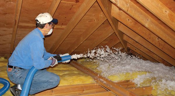 Blown-in fiberglass being installed in an attic