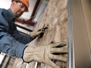 Worker installing fiberglass batts insulation into a new construction wall