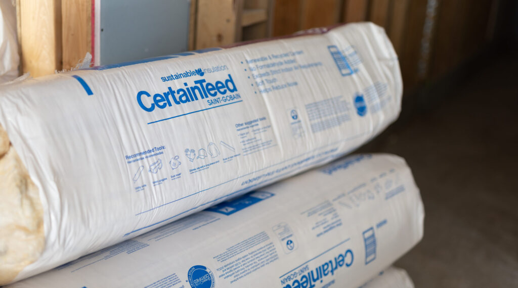 CertainTeed fiberglass batt rolls stacked on an unfinished floor
